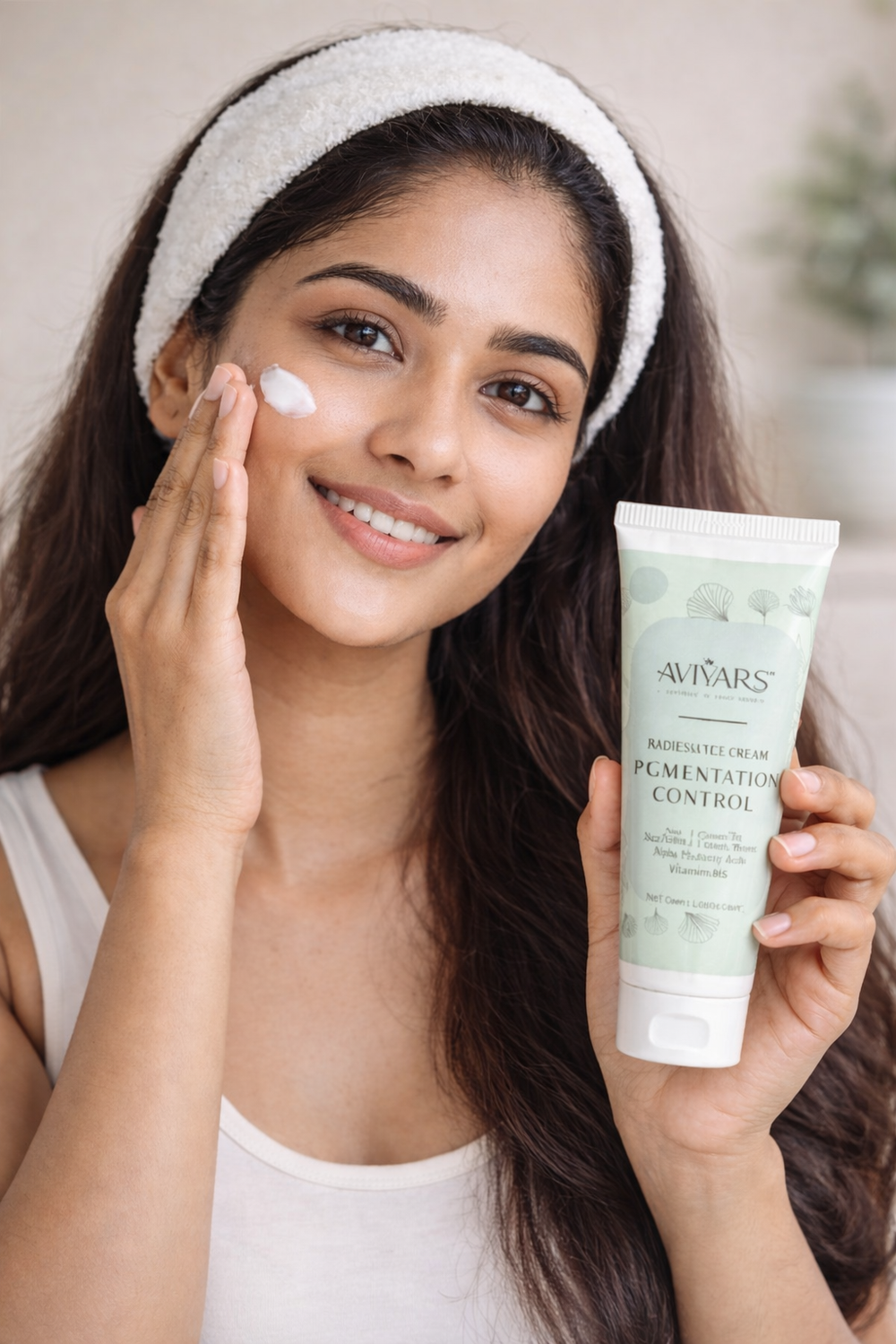 Woman applying cream to her face with a tube of Avivas skincare product.