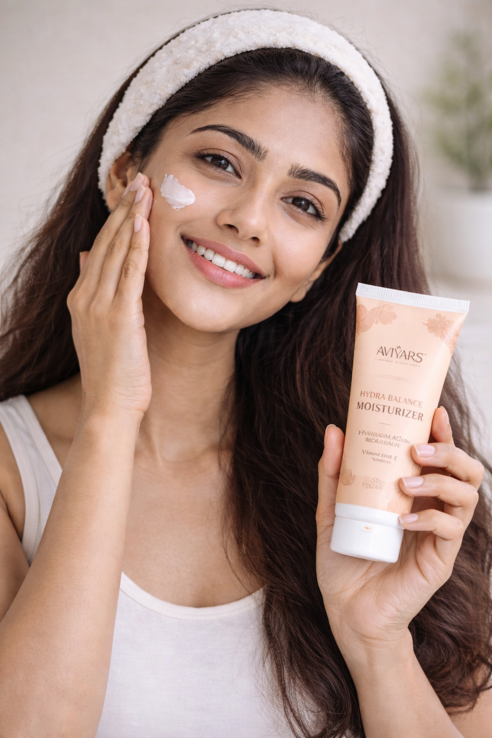 Woman applying moisturizer to her face with a tube of Avobath product.