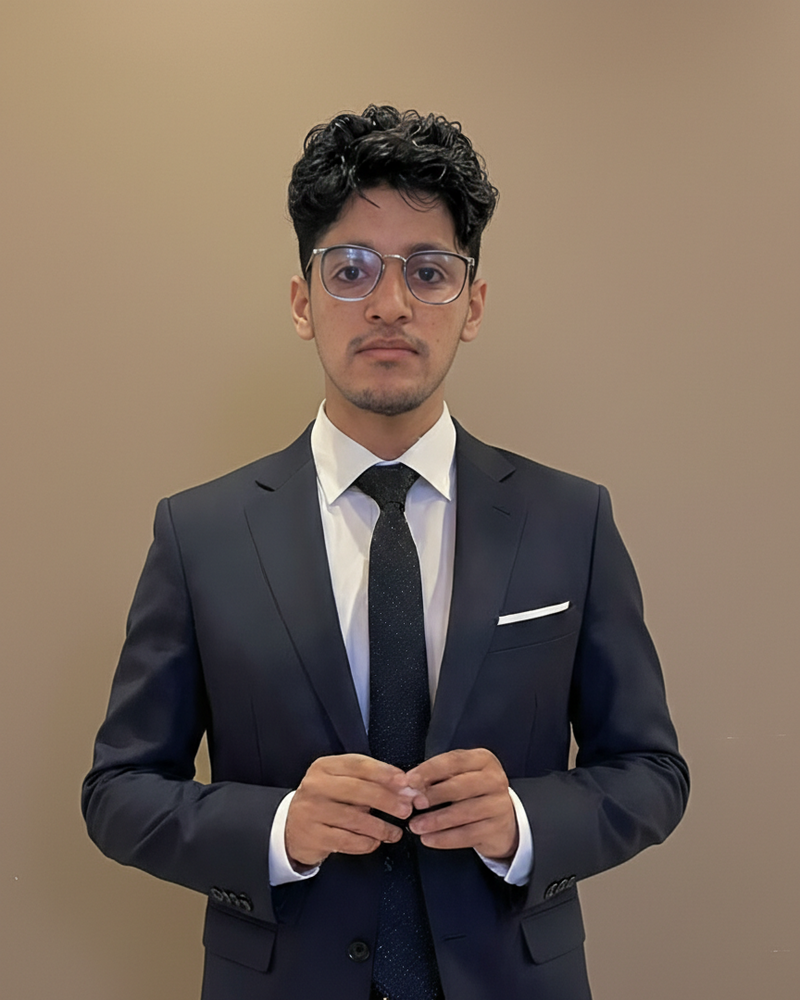 Man wearing a dark suit and tie against a beige background