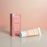 Tube of moisturizer and its packaging on a peach background